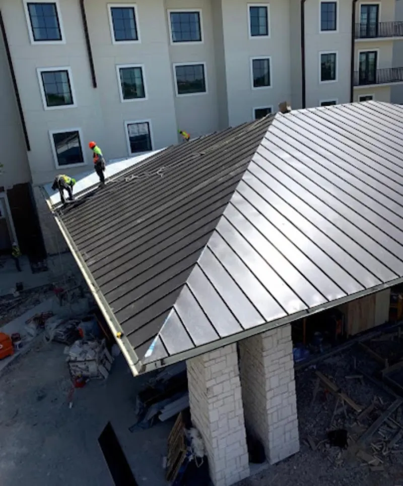 Crew installing standing seam metal roof panels on a commercial project in Wood Dale